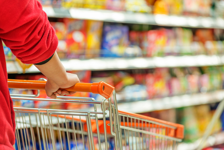 Lady pushing a shopping cart in the supermarket.